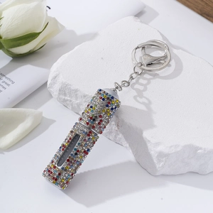Detailed view of rhinestone lipstick keychain atomizer on elegant decorative stone