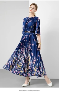 Detail van een marineblauwe geplooide midi-jurk met bloemenprint en gouden gespriem