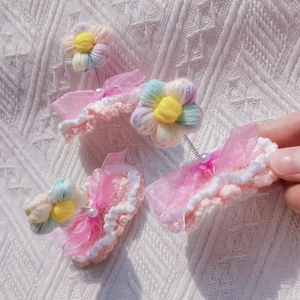 Close-up of pink crochet hair clip featuring an organza bow and spring-mounted yarn flower