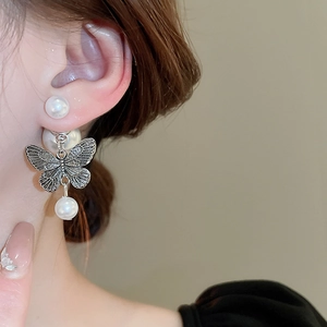 Detail of vintage butterfly earrings with faux pearls and silver metal accents