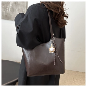 Detail der dunkelbraunen Totebag aus Öl-Wachs-Leder mit dekorativem Baseball-Anhänger
