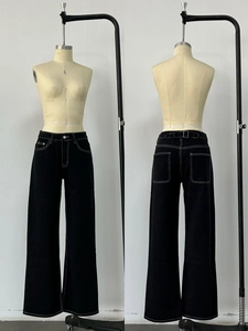Dettaglio dei pantaloni in denim nero a vita alta con cuciture a contrasto bianche