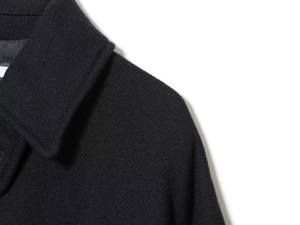 Detail of the high-quality black textured wool fabric on the collar and shoulder of the jacket
