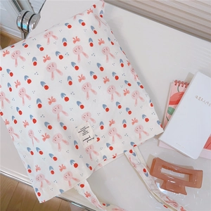 Close-up of white cotton tote bag with cute rabbit and cherry patterns in a desk scene