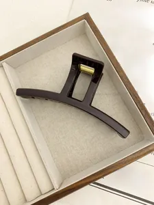 Detail of a large dark brown high-gloss hair claw clip in an elegant jewelry box