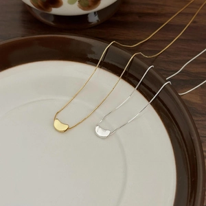Minimalist 925 sterling silver bean necklaces in gold and silver finish on a ceramic plate