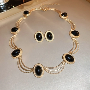 Detailed view of vintage gold necklace and stud earrings set with oval black gemstones