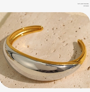 Close-up of chunky mixed metal cuff bracelet in gold and silver on stone background