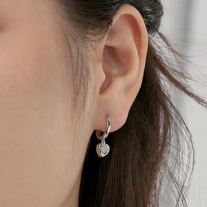 Close-up of heart-shaped zircon silver drop earring worn on a model's earlobe