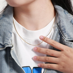 Detailed close-up of a slim golden snake bone chain necklace worn on a model's neck