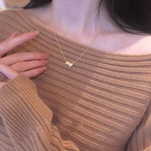 Close-up of interlocking puzzle pendants in gold and silver on a woman's neckline