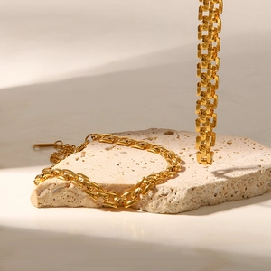 Présentation artistique d'un bracelet à gros maillons en or 18 carats sur pierre beige