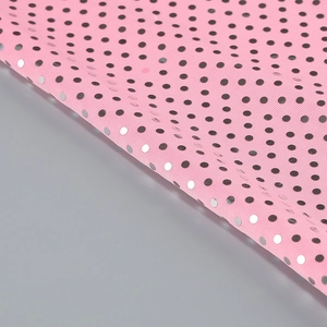 Detailed close-up of pink sequined fabric with silver and black metallic polka dots