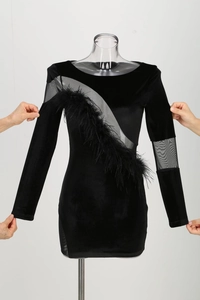 Detail of velvet mini dress featuring sheer mesh panel and black feather trim decoration