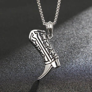 Macro shot of silver titanium steel cowboy boot pendant with star relief and metal chain