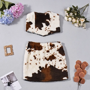 Flachgelegte braun-weiße Samt-Kombi aus Crop-Top und Minirock mit Kuhmuster und Pelztextur