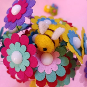 Close-up of handmade yellow wool felt bee and colorful flower DIY accessory