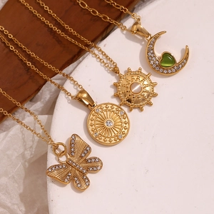 Detailed macro view of 18K gold plated moon and butterfly pendants with inlaid crystals