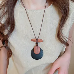 Ethnic vintage wooden bead necklace with geometric circular pendant on linen clothing