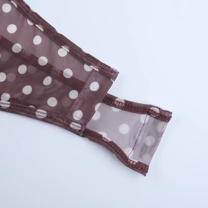 Détail d'un body en tulle marron avec pois blancs et coutures fines sur le tissu