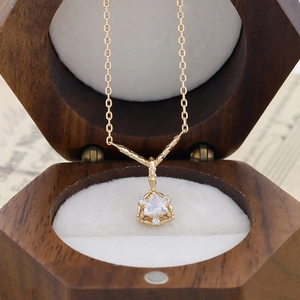 Dettaglio della collana con gemma triangolare e tre diamanti in scatola di legno