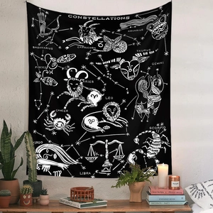 Détail d'une tapisserie bohème noire avec signes du zodiaque blancs dans une pièce cosy