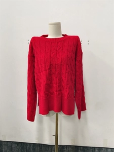 Detailed close-up of the red chunky cable knit pattern and round neck on a casual sweater