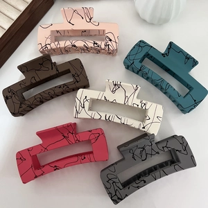 Detailed top view of 6 matte colorful hair claws with abstract black ink patterns