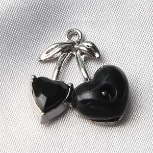 Macro shot of cherry-shaped jewelry charm with black faceted stones and silver metal loop