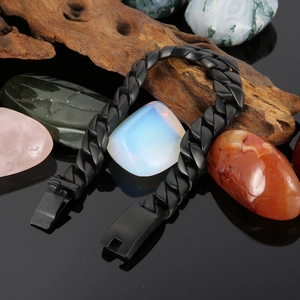 Nahaufnahme des schwarz matten Titan-Panzerarmbands auf Holz mit Natursteinen dekoriert