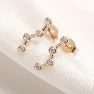 Star and moon gold plated earrings with zircon stones on white silk fabric background