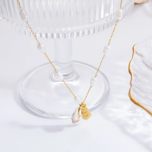 Detail of gold pearl necklace with shell pendants on a translucent glass holder
