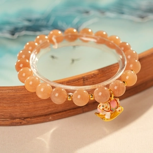 Close-up of natural sunstone beaded bracelet with a colorful enamel rocking horse charm