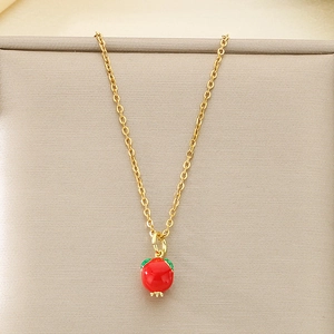 Detail of gold necklace with red pomegranate enamel pendant on display cushion