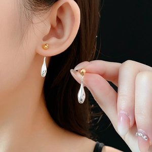 Detail of two-tone gold and silver teardrop earrings worn on model's ear