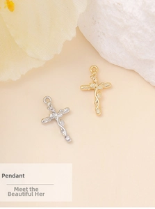 Dettaglio di ciondoli a croce in oro e argento con trame intrecciate di viti e foglie
