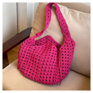 Dettaglio macro della borsa tote intrecciata rosso rosa con trama traforata sul divano