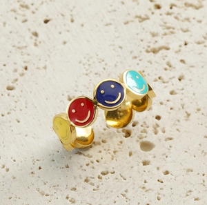 Detail of colorful enamel smiley face open rings on a textured stone surface