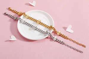 Detail of gold and silver pineapple charm bracelets with Cuban links on a ceramic plate