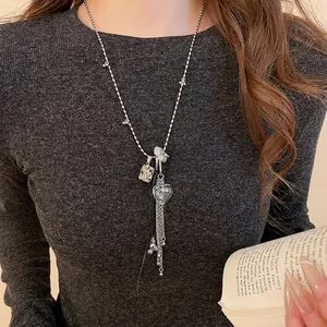 Collana color argento con ciondolo a cuore e quadrato con nappe su maglione grigio scuro