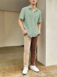 Detail of short sleeve knit shirt and bicolor trousers on model in a modern urban setting