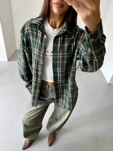 Detail of green and black plaid shirt featuring a classic collar and single chest pocket