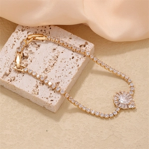 Macro shot of gold-plated pear-cut zircon bracelet on beige stone and silk backdrop