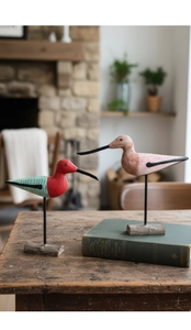 Detail of handcrafted wooden bird statues on metal stands with vintage book and home decor