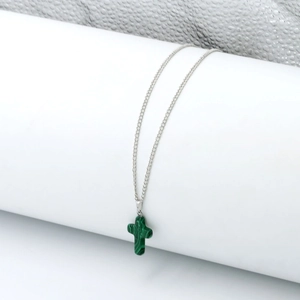 Detail of silver chain with green malachite cross pendant on a white display stand