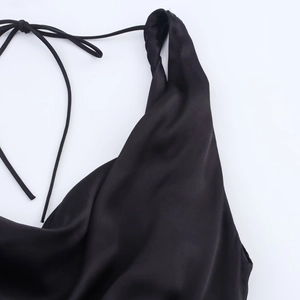 Detail view of black satin dress featuring thin adjustable straps and luxury texture
