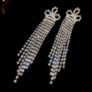 Detailed view of silver bow-shaped long tassel earrings with sparkling white rhinestones