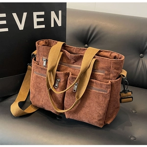 Close-up of brown corduroy tote bag showing textured vertical ribs and dual front zipper pockets