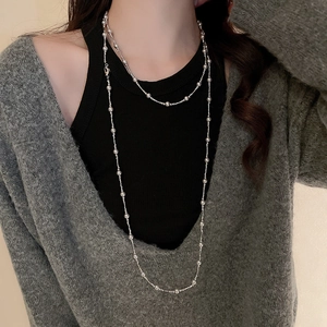 Détail d'un collier multicouche en perles argentées avec pendentif croissant