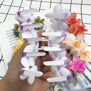 Close-up of a large purple frangipani flower hair claw clip in hand for size display